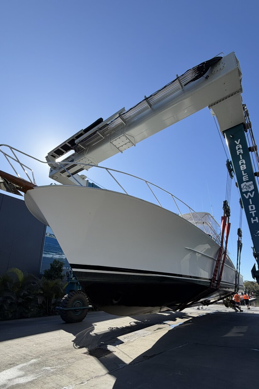 Bow of a sportfishing vessel supported in a travel lift, hull and running gear exposed for inspection