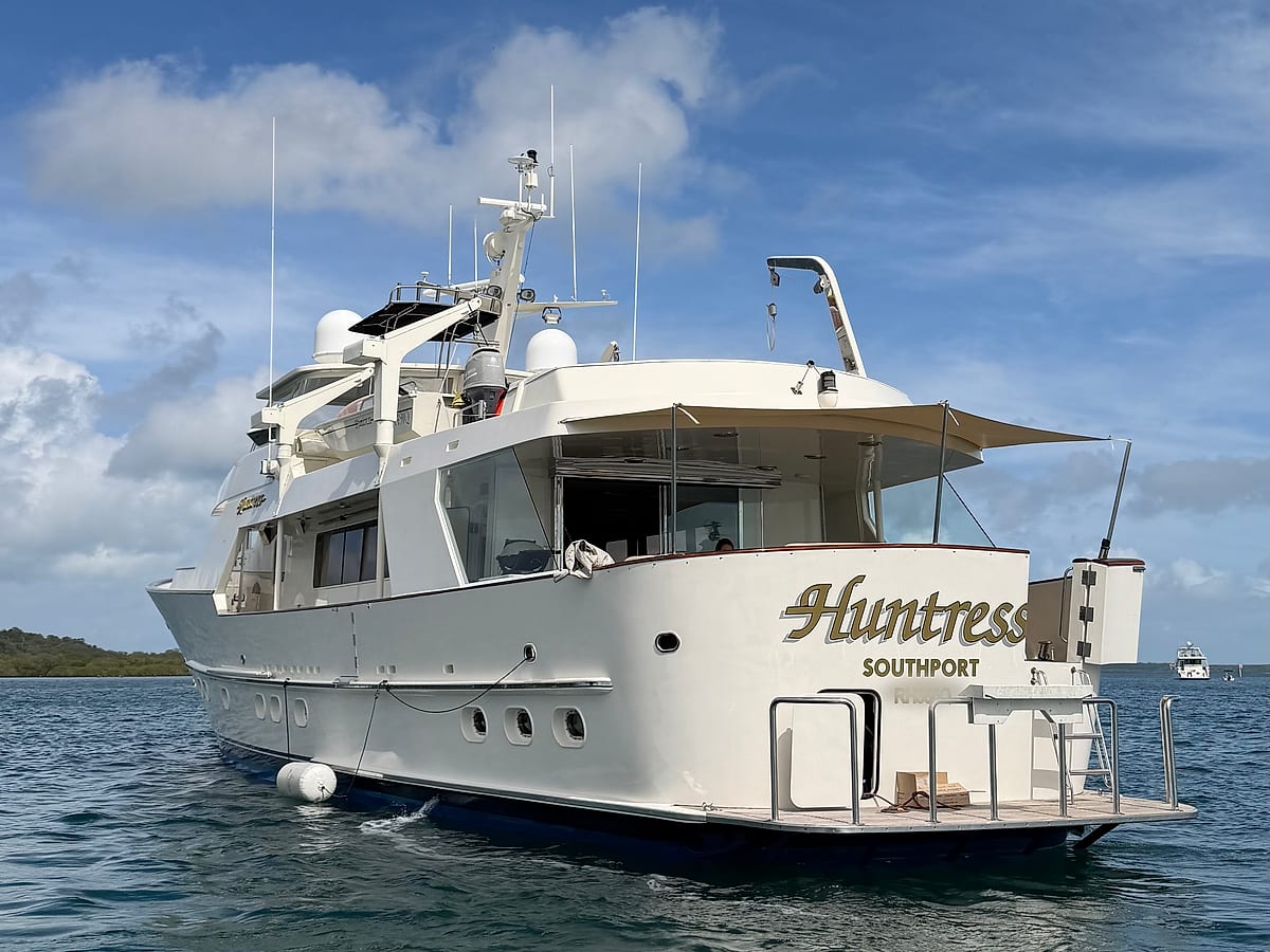 Large white luxury motor yacht at rest on calm water, supported by Prestige VMT